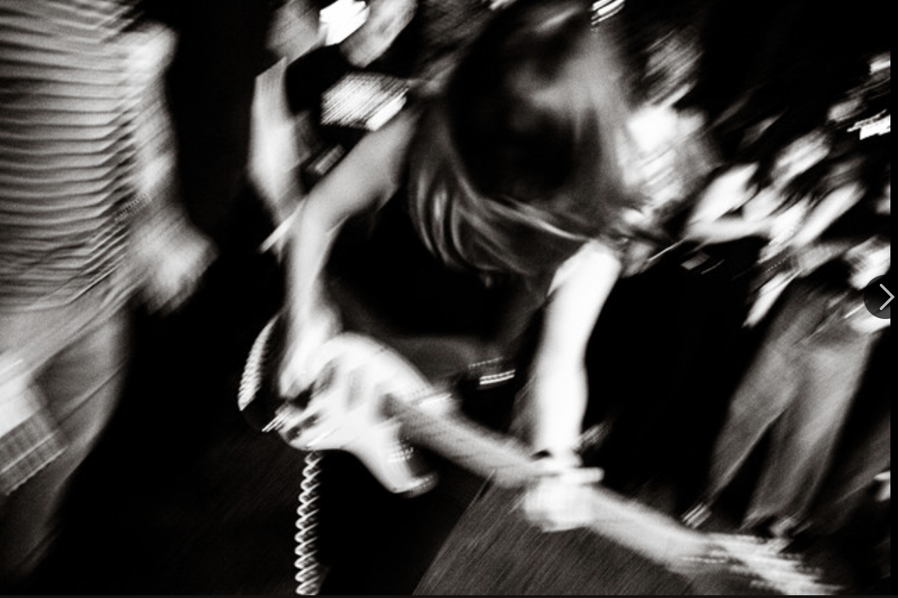 Blurry black and white image of person playing the guitar<br />
